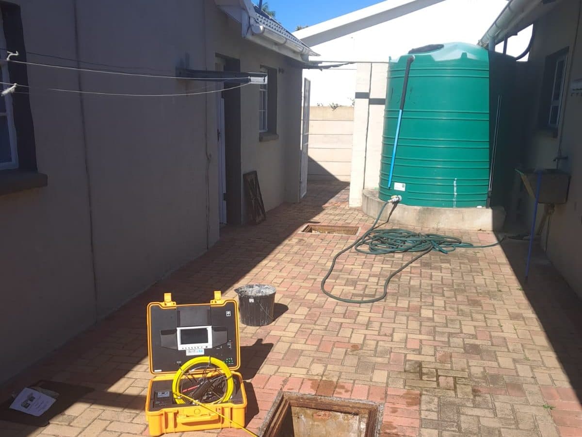 Drain cleaning machine set up in a paved backyard in Gqeberha