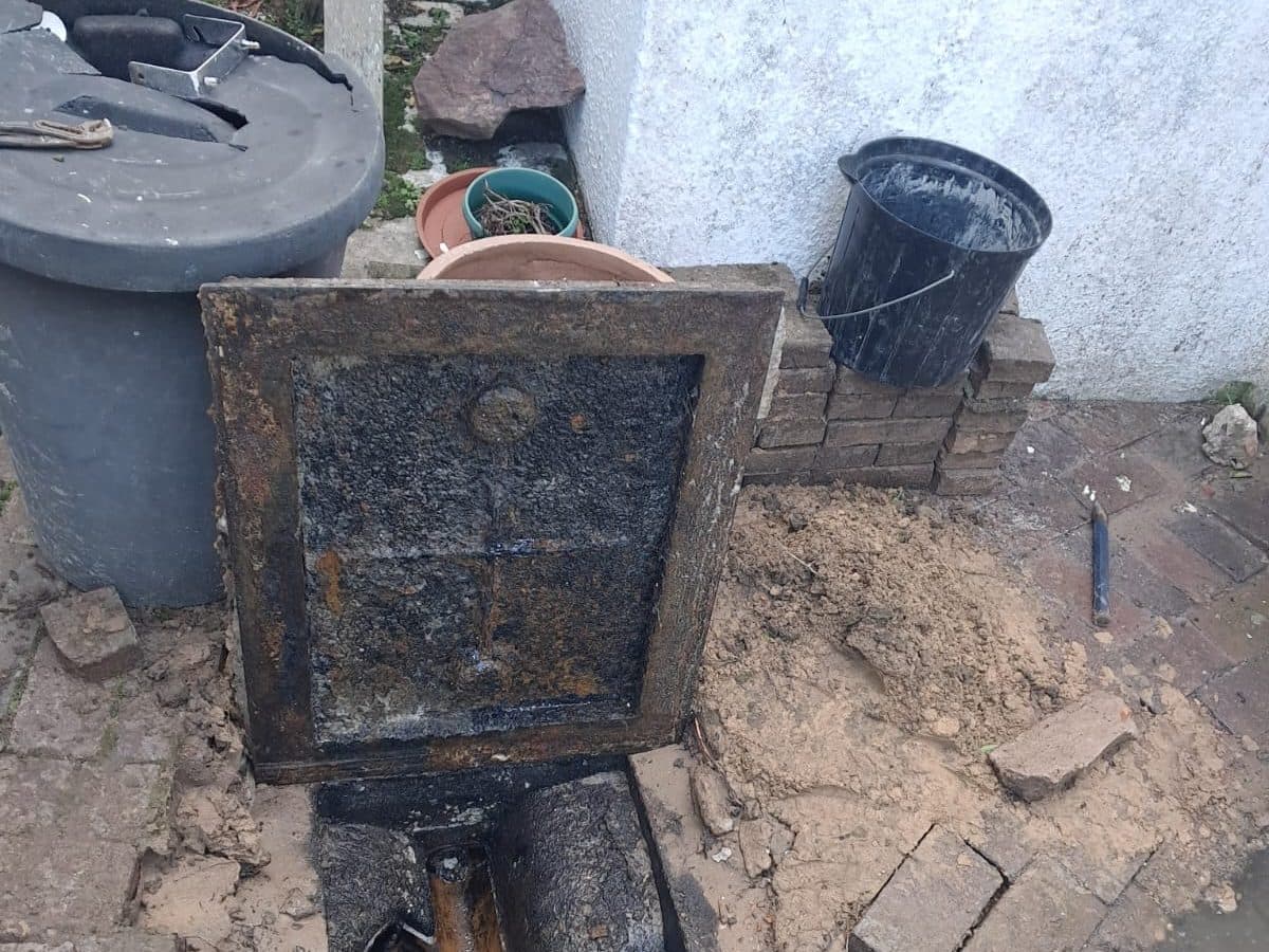 Drain manhole opened up beside a house