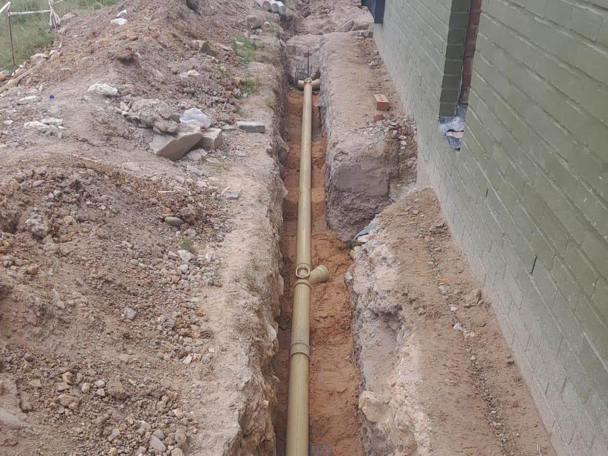 Drain trench dug through rubble and soil