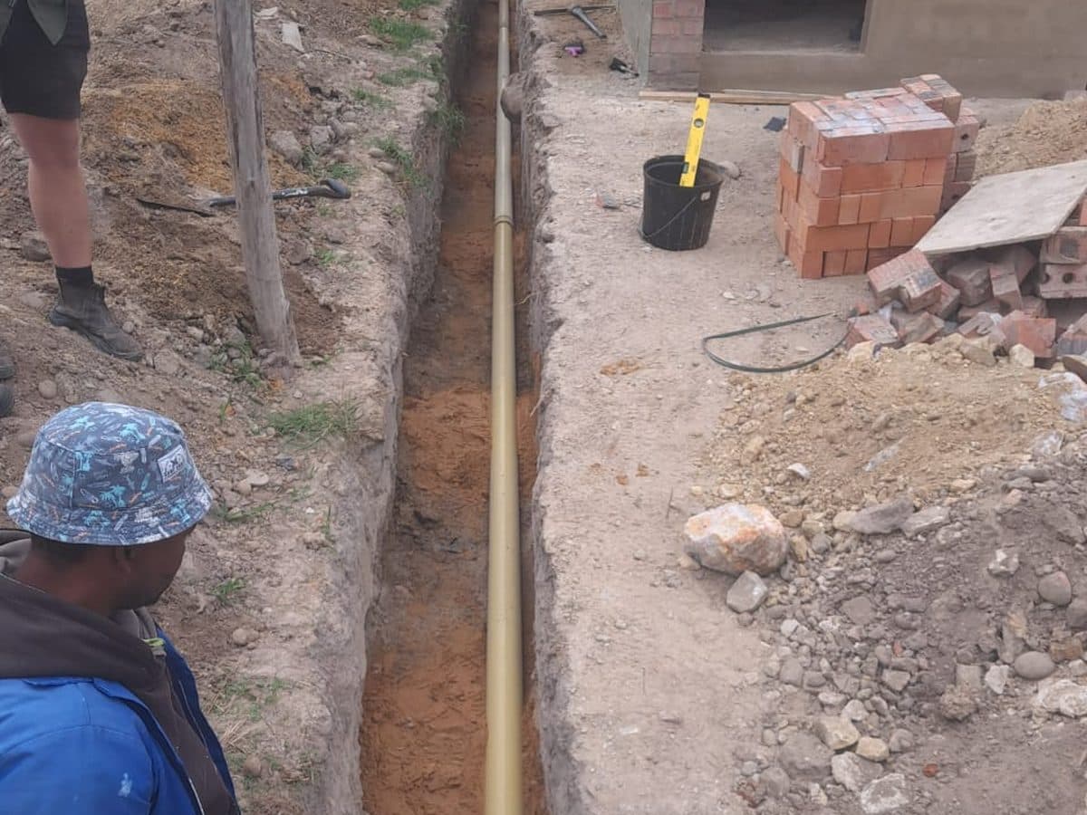 Technician beside an open drain trench
