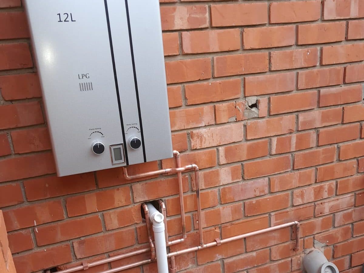 Geyser electrical connection and pipework on a brick wall