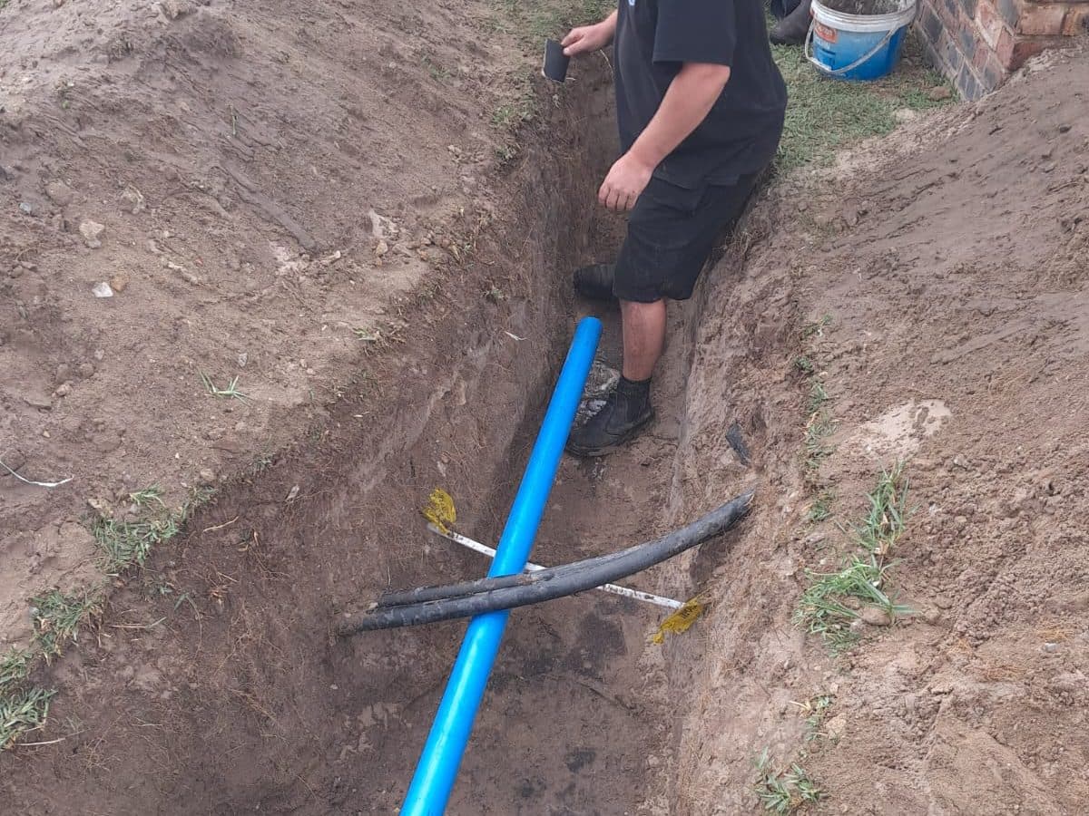 Technician laying pipe in a service trench