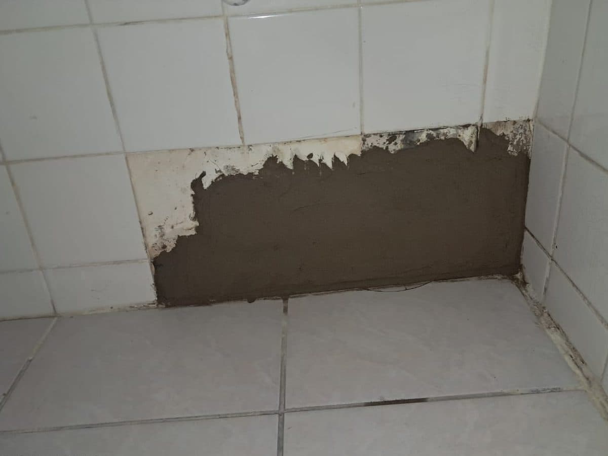 Wall opened up behind the tiles to reach a pipe