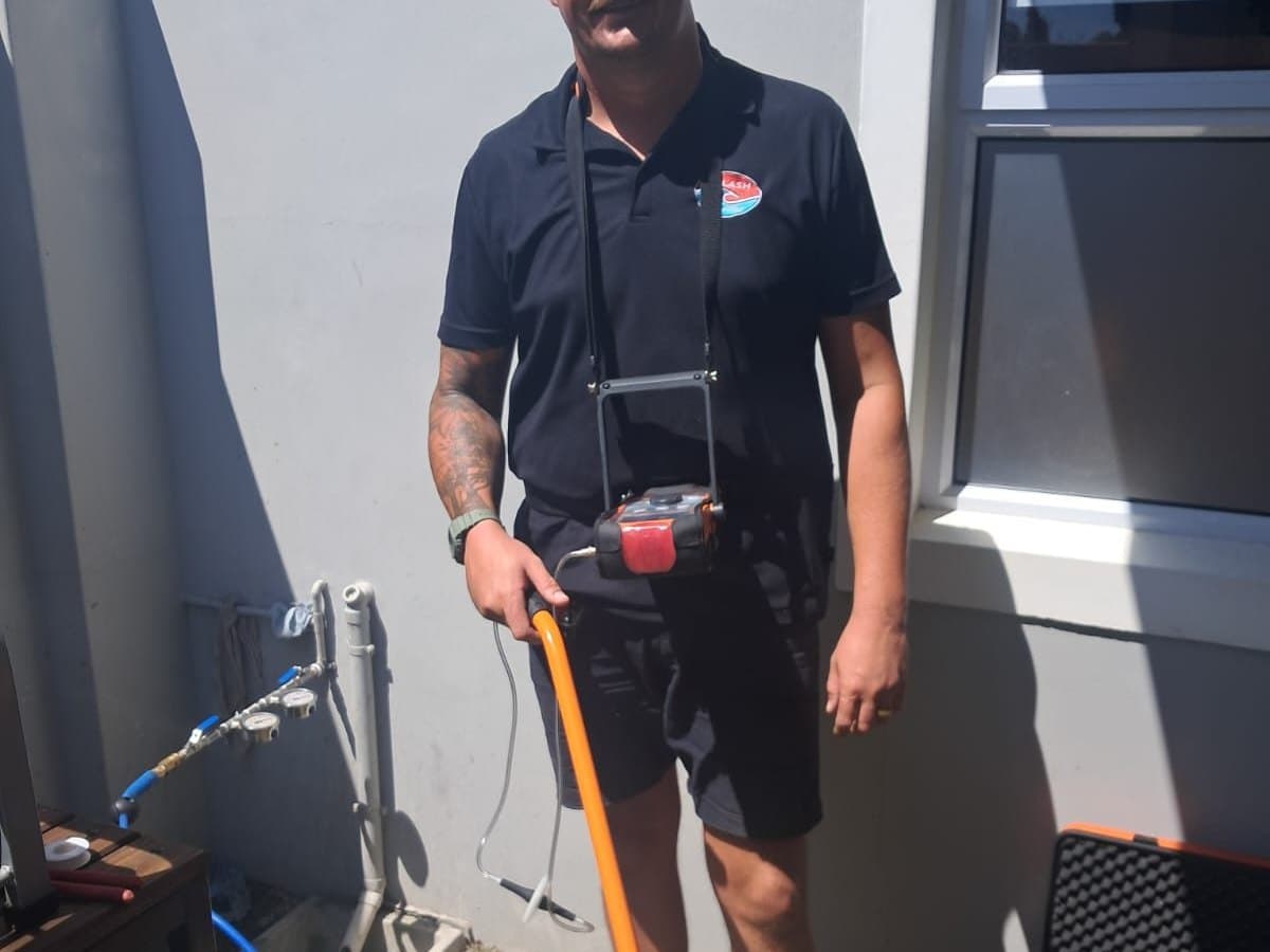 Technician checking pipework with leak detection equipment