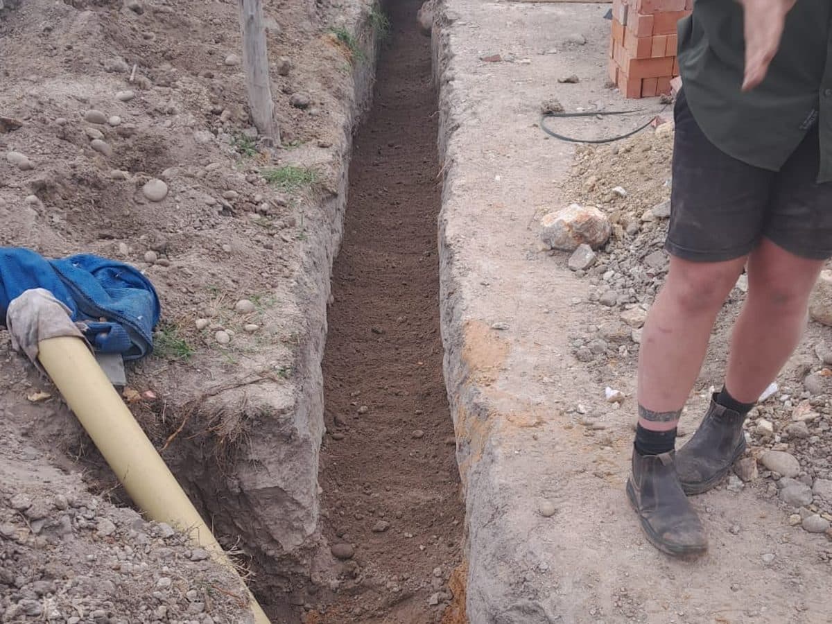 Worker beside an open service trench on site