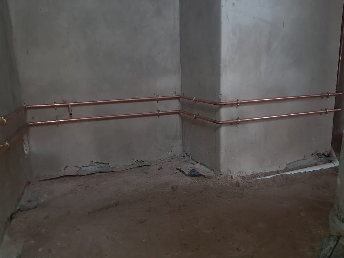 Copper pipework along a new concrete wall