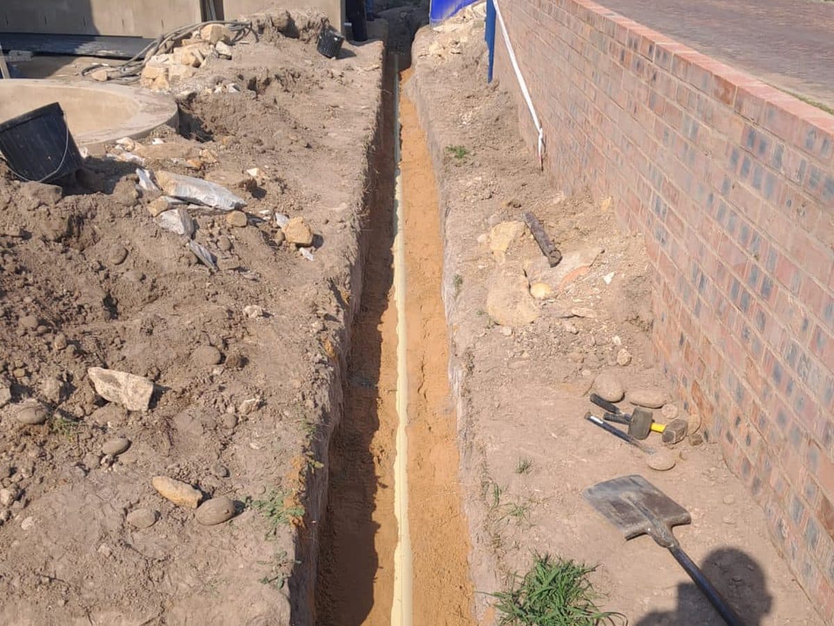 Service trench beside a brick wall on site